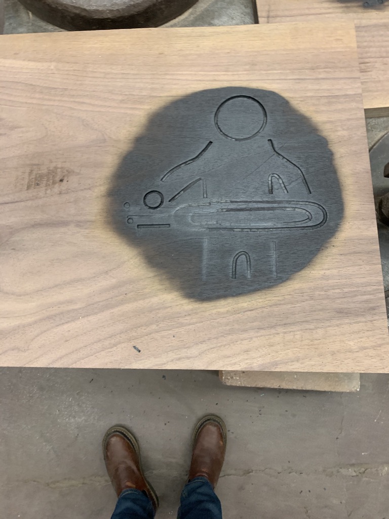 Wood plank with custom branded logo mark from branding iron, shown with work boots for scale
